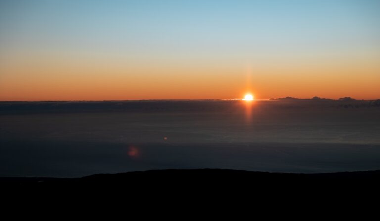 die Sonne geht über dem Horizont eines großen Gewässers unter